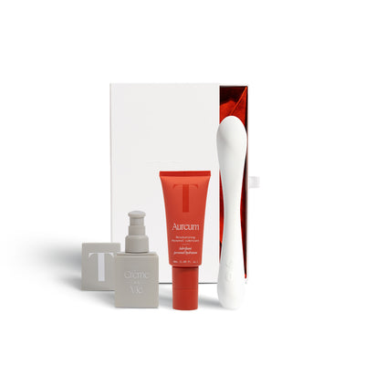 A picture of the golden hour kit box displaying the items of the bundle in front of it: Creme de la Vie vulva moisturizer, Aureum water based lubricant, and the Nuri wand massager.